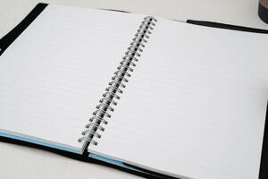 Blank paper notebook on brown wooden table background. Top view with copy space photo