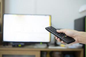 The women with the remote control in hand watching the channel and presses the button on the remote control. photo