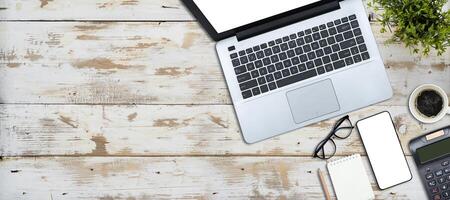 Wooden table top with plant pots, laptop, calculator, glasses, notebook photo