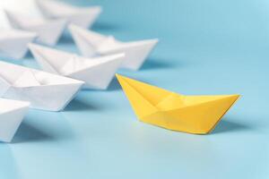 Leadership concept, yellow leader boat leading black boats, on blue background with empty copy space. photo