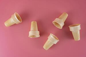 Empty ice cream cone on pink faded pastel color background photo