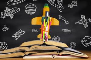 rocket placed over a book in front of a blackboard depicting space objects in the classroom. photo