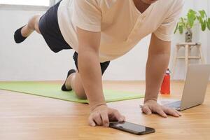 man with tablet computer doing running plank exercise at home photo