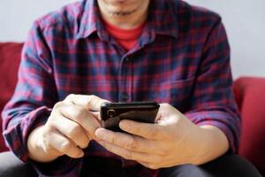 Glad fashionable young bearded guy wears stylish clothes and denim shirt, uses free internet connection photo
