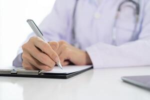 Doctor with a clipboard wrote on paper at the desk in the office. photo
