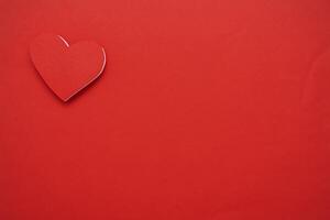 Red paper hearts isolated on red background. On the top left there is an empty space photo