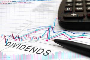 DIVIDENDS text on documents with graphs, charts, calculator, pen photo