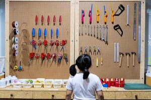 A girl is choosing tools on the table and board. Workshop scene concept photo