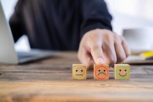 Close up customer hand choose sad face and smiley face icon on wood cube, Service rating, satisfaction concept photo