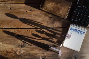 Budget planing concept. Top view of notepad with word budget, calculator, cup of coffee, family silhouette, pouch on wooden background photo