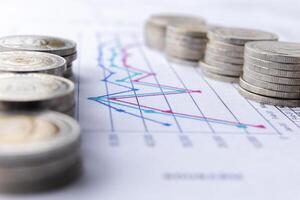 Closeup stacks of Thai baht coins on graphs and charts background photo