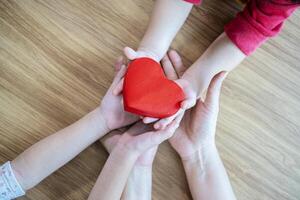 adult and child hands holding red heart on aqua background, heart health, donation, CSR concept, world heart day, world health day, family day photo