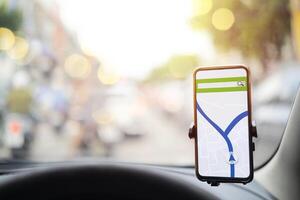 The map on the phone in the background of the dashboard. Black mobile phone with map gps navigation fixed in the mounting. photo