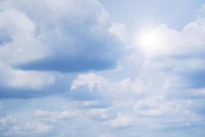 The sky is full of clouds floating around, both small and large, the sun is shining brightly photo