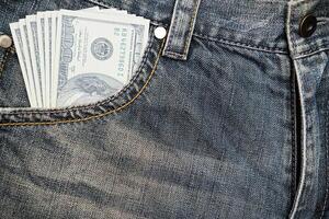 A dollar bill inserted in a jeans pocket. It is cash in a pocket and has cash on hand photo