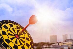 Red dart arrow hit in the target center of dartboard with sky background, Target hit in the center by arrows photo