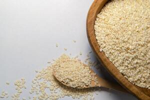 White sesame seeds or cumin in spoons on Gray isolated background, top view, close up photo