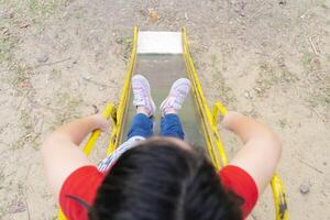 Cute asian child girl having fun to play slider in the playground in summer time photo