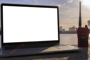 The tablet screen is blank for text and radio communication. The backdrop is an industrial project. photo