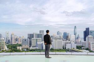 Businessman standing on building. City background with copy space. Success and vision concept photo