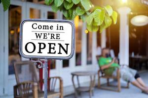 Closeup Metal signs placed in front of the shop is labeled Come on in We're OPEN photo