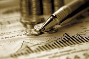 Close up of a pen on financial charts with coins in the background photo