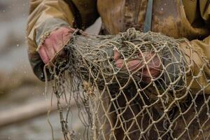 Close up of a fisherman's hands mending a fishing net, with meticulous care and skill photo