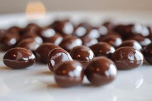 Closeup view of glossy chocolatecovered almonds arranged on a white surface photo