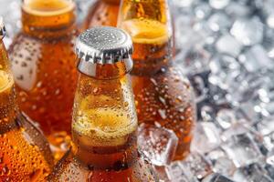 Group of wet brown beer bottles chilling in ice water photo