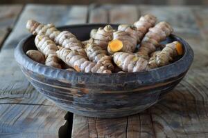 Fresh turmeric root in a rustic wooden bowl photo