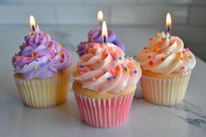 Delicious birthday cupcakes with lit candles and sprinkles on white background photo