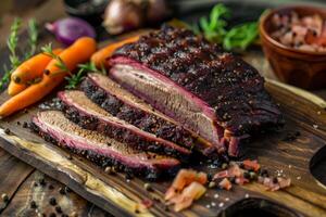 Smoked beef brisket lying on a wooden cutting board with carrots and spices photo
