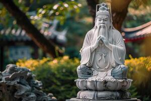 White statue of confucius sitting peacefully in a public park photo