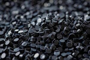 Black plastic polymer granules forming a pile for further processing photo
