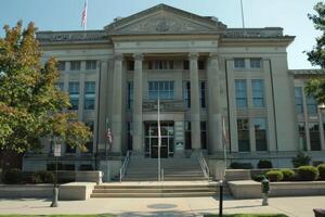 American courthouse building facade with columns and flags displayed on sunny day photo