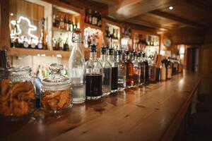 Inviting bar scene with neatly arranged jars and bottles on a wooden countertop. Warm lighting and cozy ambiance suggest a well stocked establishment. photo