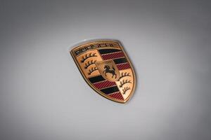 Porsche emblem with gold, black, and red colors on light background. Features Wurttemberg and Stuttgart coat of arms elements. Glossy finish adds depth. photo