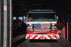 Fire station garage with red and white Chevrolet truck from Colorado at the forefront, ready for deployment. Sparks Fire Rescue fire engine parked in the background. Urban setting. photo