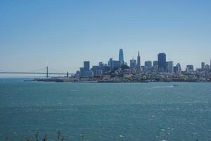 Panoramic view of San Francisco skyline from a vantage point, featuring San Francisco Bay, Bay Bridge, skyscrapers like Salesforce Tower and Transamerica Pyramid, serene atmosphere. photo