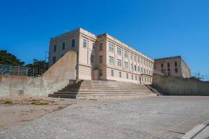 View the iconic Alcatraz prison in San Francisco, USA, showcasing a grand beige building with multiple windows, a central entrance, and two sets of stairs. photo