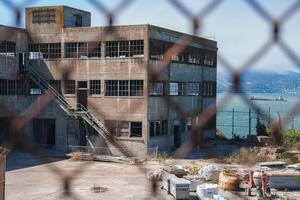 Dilapidated building in Alcatraz prison complex, San Francisco, USA. Multi storied with broken windows, leading up to stairs, debris. Isolated island penitentiary vibe. photo