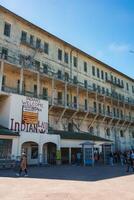 Alcatraz prison scene in San Francisco, USA. Aged building with barred windows and INDIANS WELCOME sign. Tourists, peaceful atmosphere, bird flying. photo