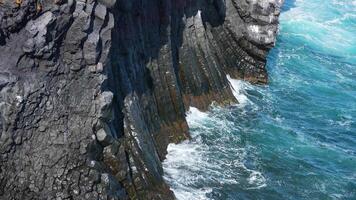 Close up view of the waves in blue ocean with basalt cliff in Iceland video