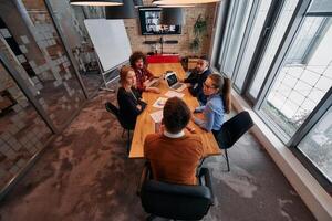Top view of a modern startup office, a diverse team of business professionals engage in discussions on various projects and develop new business strategies, epitomizing creativity and innovation in photo
