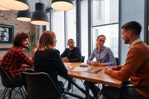 In the vibrant ambiance of a modern startup office, a diverse team of business professionals engage in discussions on various projects and develop new business strategies, epitomizing creativity and photo