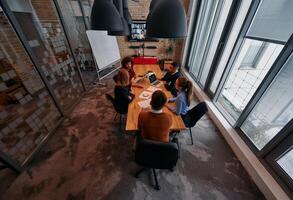 Top view of a modern startup office, a diverse team of business professionals engage in discussions on various projects and develop new business strategies, epitomizing creativity and innovation in photo