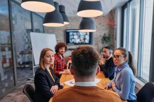In the vibrant ambiance of a modern startup office, a diverse team of business professionals engage in discussions on various projects and develop new business strategies, epitomizing creativity and photo