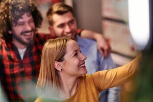 A diverse group of business professionals take a break from their tasks in a modern startup office to capture a creative selfie, showcasing teamwork and a vibrant workplace culture photo