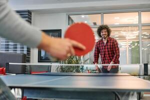 Business colleagues take a break from work to enjoy a game of table tennis, fostering teamwork and camaraderie in the workplace photo
