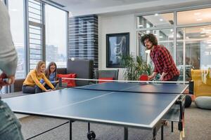 Business colleagues take a break from work to enjoy a game of table tennis, fostering teamwork and camaraderie in the workplace photo
